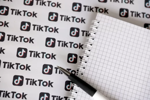 Notepad with pen and Many TikTok logo printed on paper
