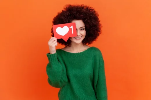 Happy positive young adult woman covering her eye with social media heart Like icon