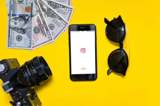 instagram app on phone next to dollars and camera