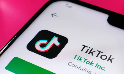 TikTok app in Google Play seen on the corner of the smartphone placed on pink surface